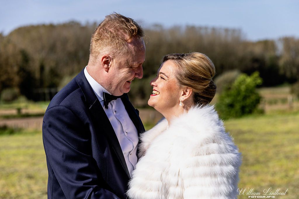 A romantic winter wedding moment captured as a couple embraces outdoors with the bride wearing a white fur wrap.