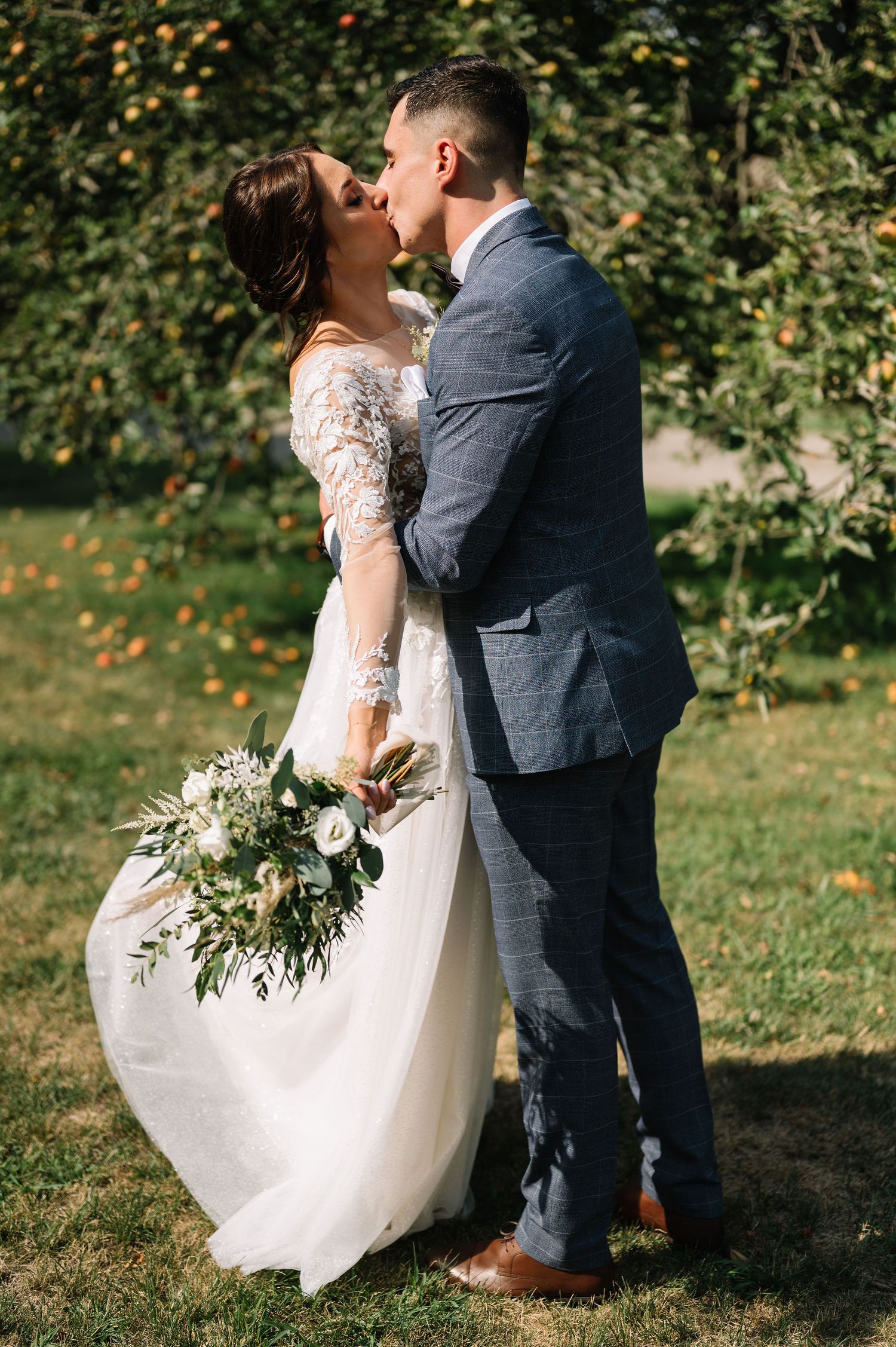 Newlyweds share a romantic moment in a garden, bride holding a lush bouquet.