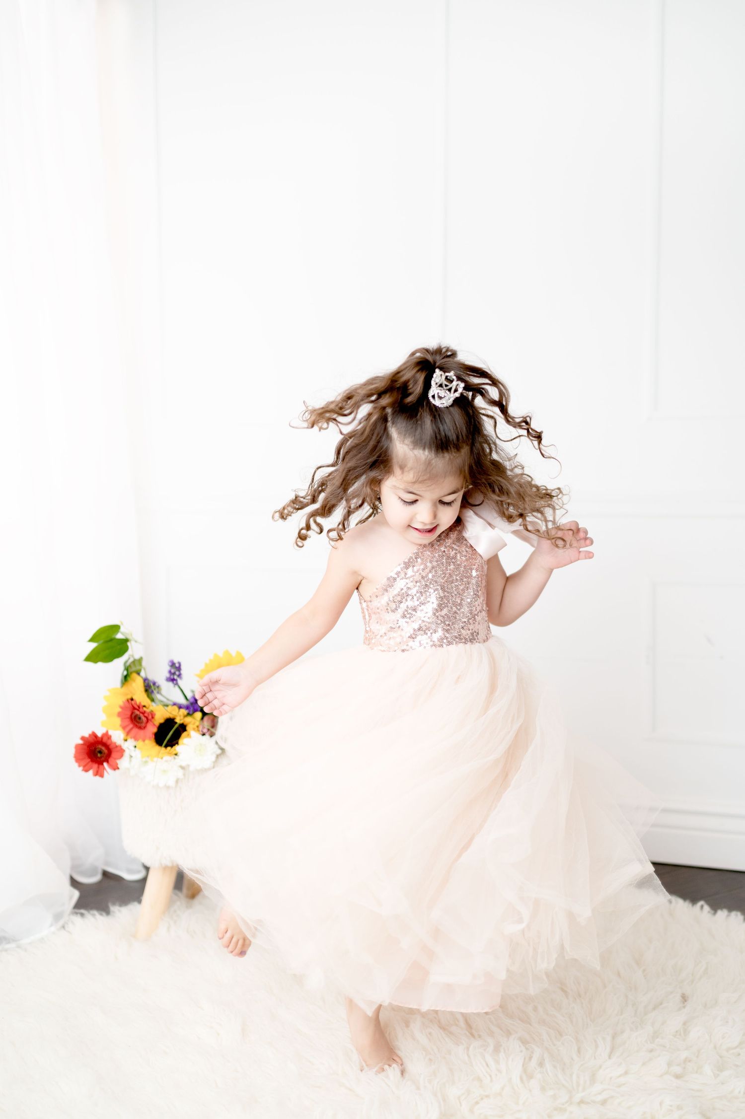 A dynamic spin captured in a sparkly pink dress against a clean white studio setting.
