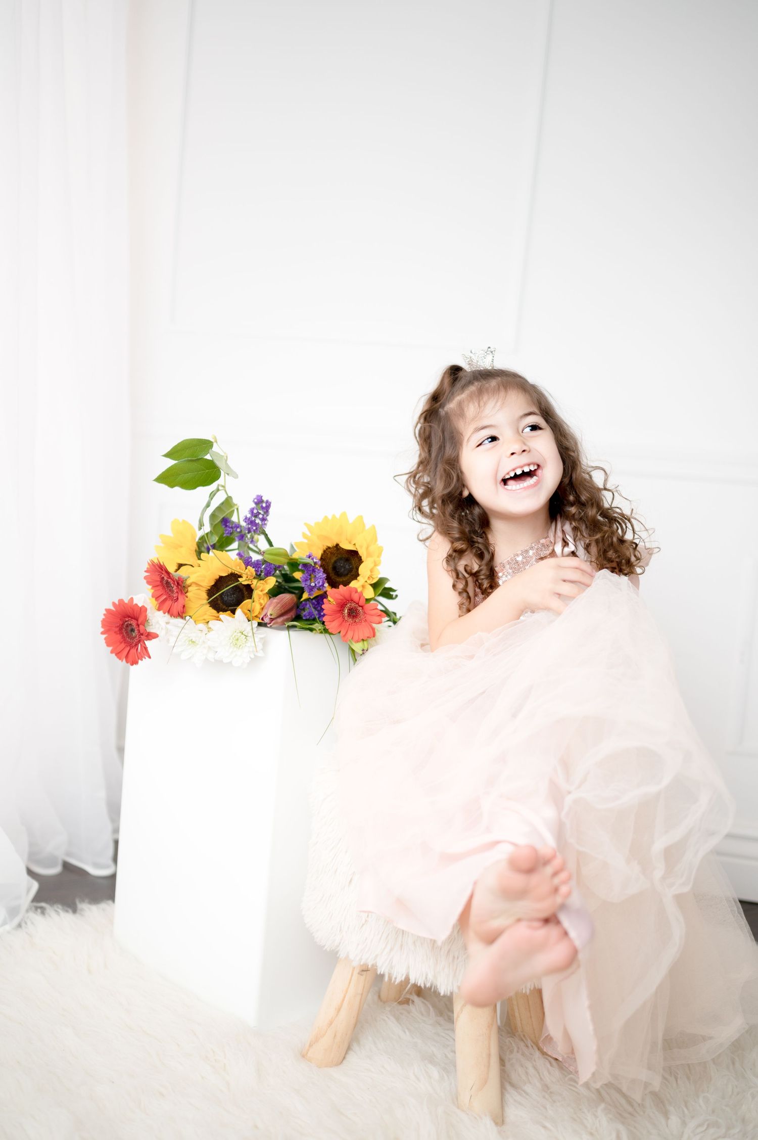 A candid laughing moment on a stool beside bright sunflowers and wildflowers.