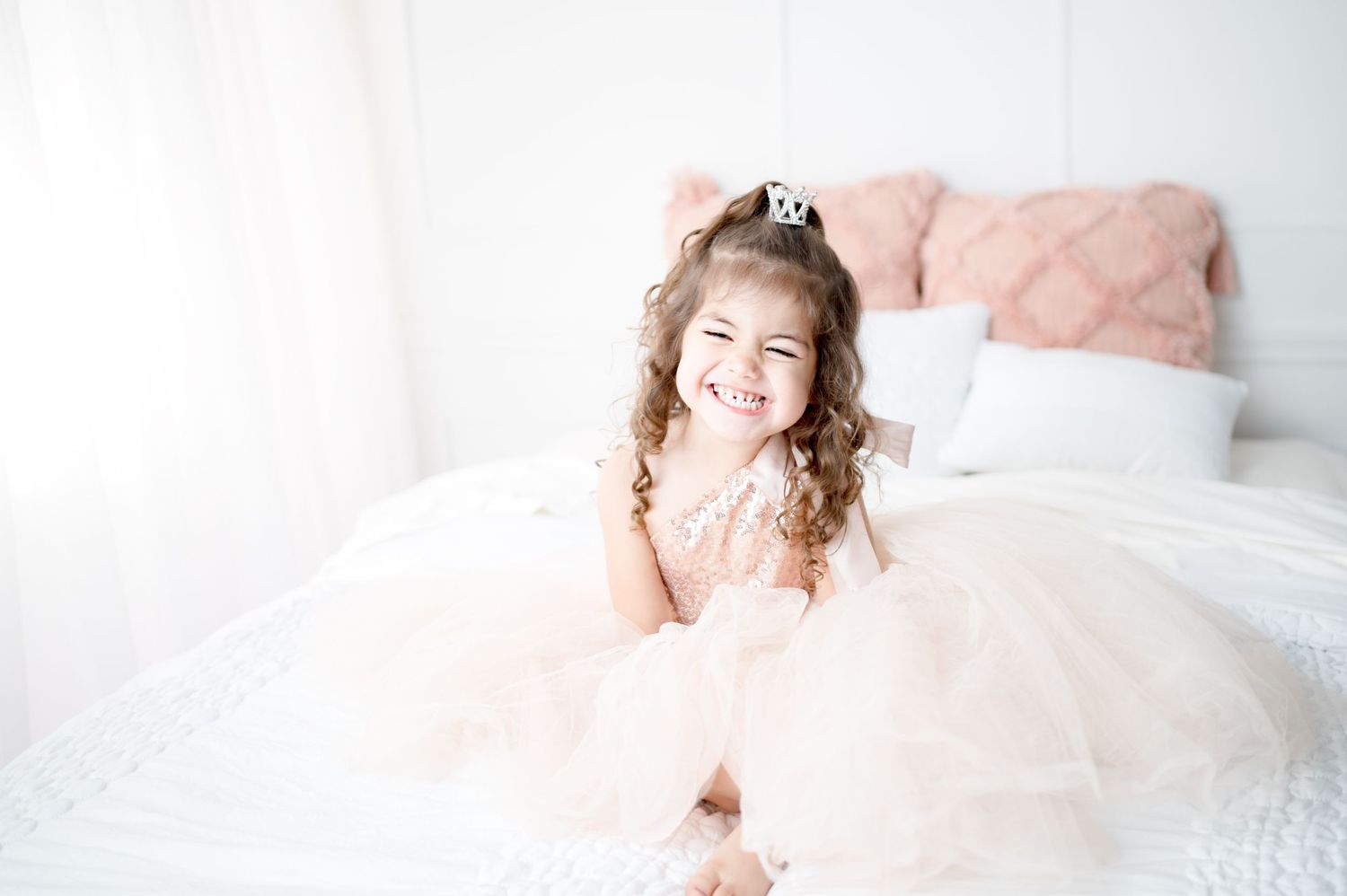 A bright and airy bedroom portrait with soft pink decor and joyful energy.