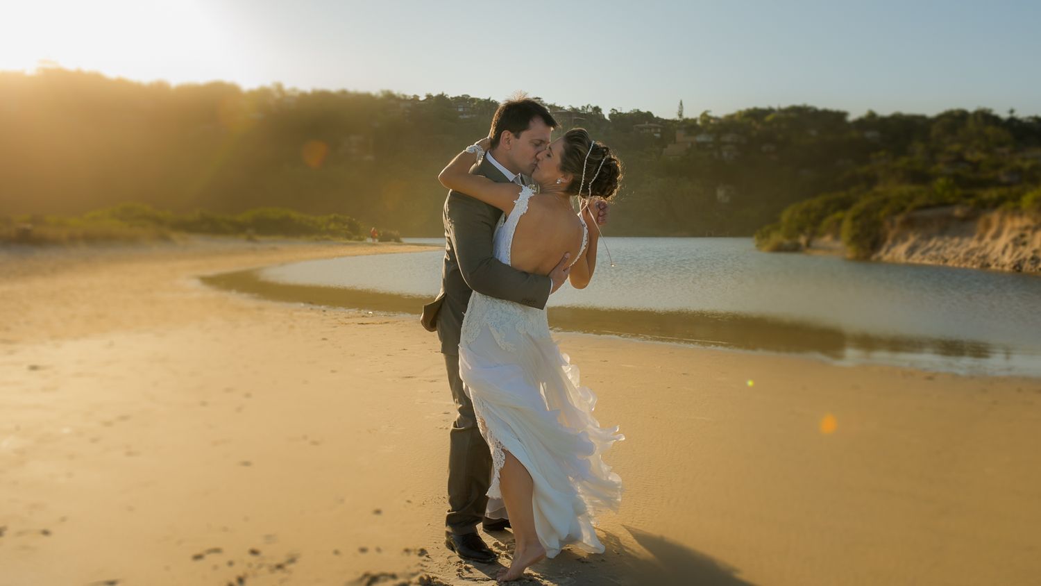 A romantic sunset beach moment with water and cliffs in the background.