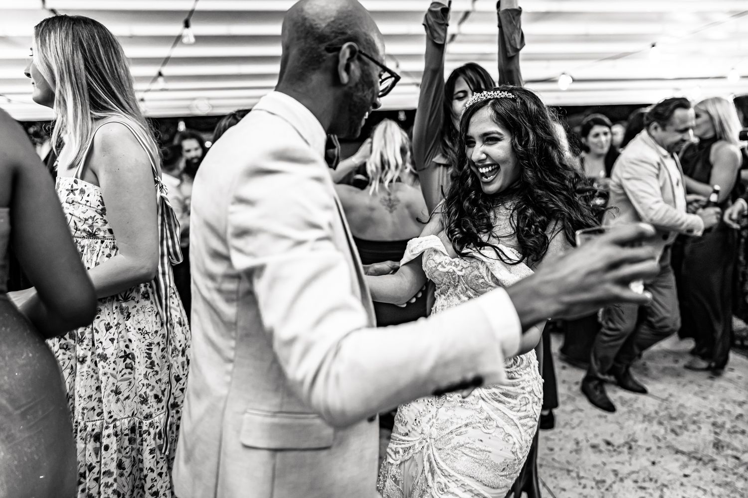 A couple dances together at a wedding reception in black and white.