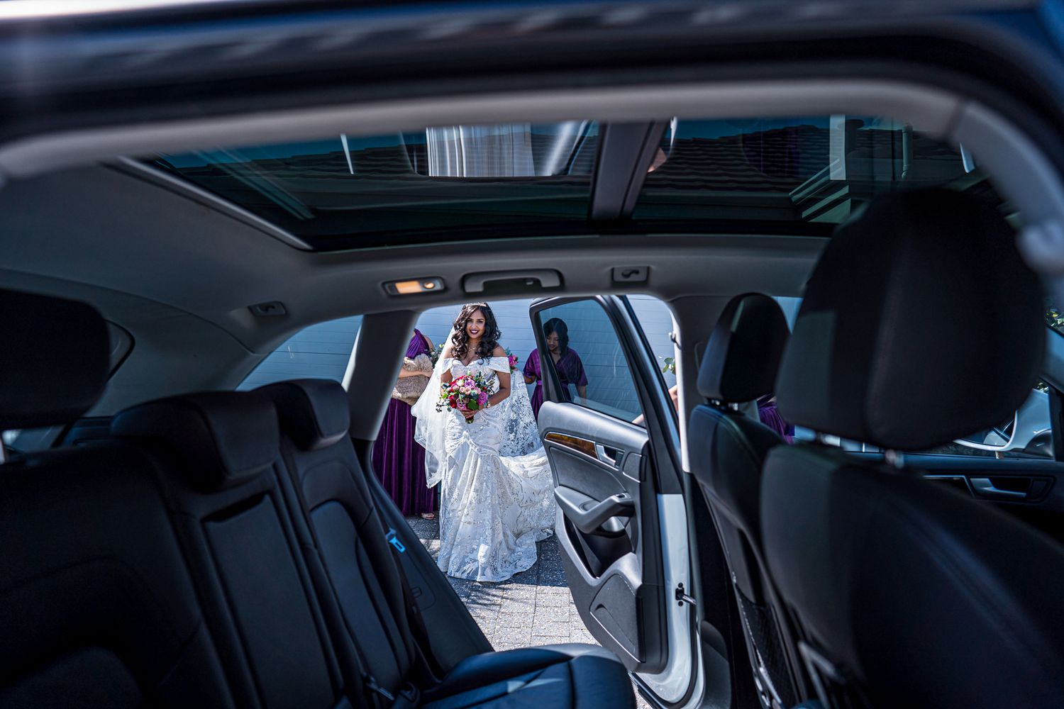 View through a car interior showing a wedding dress through an open door.