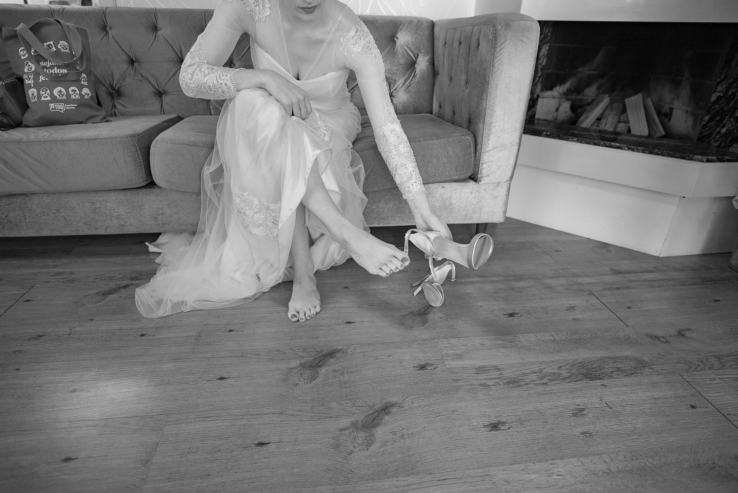 Black and white image of wedding preparation showing shoes being put on over wooden flooring.