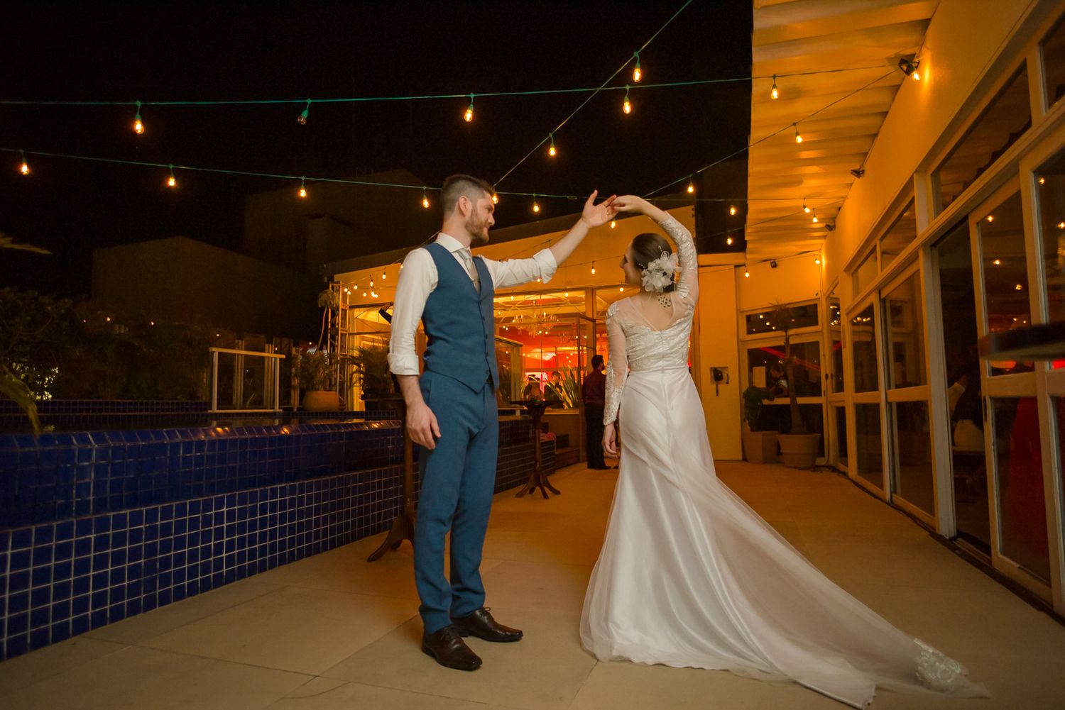 Couple performs first dance under string lights at evening wedding reception.