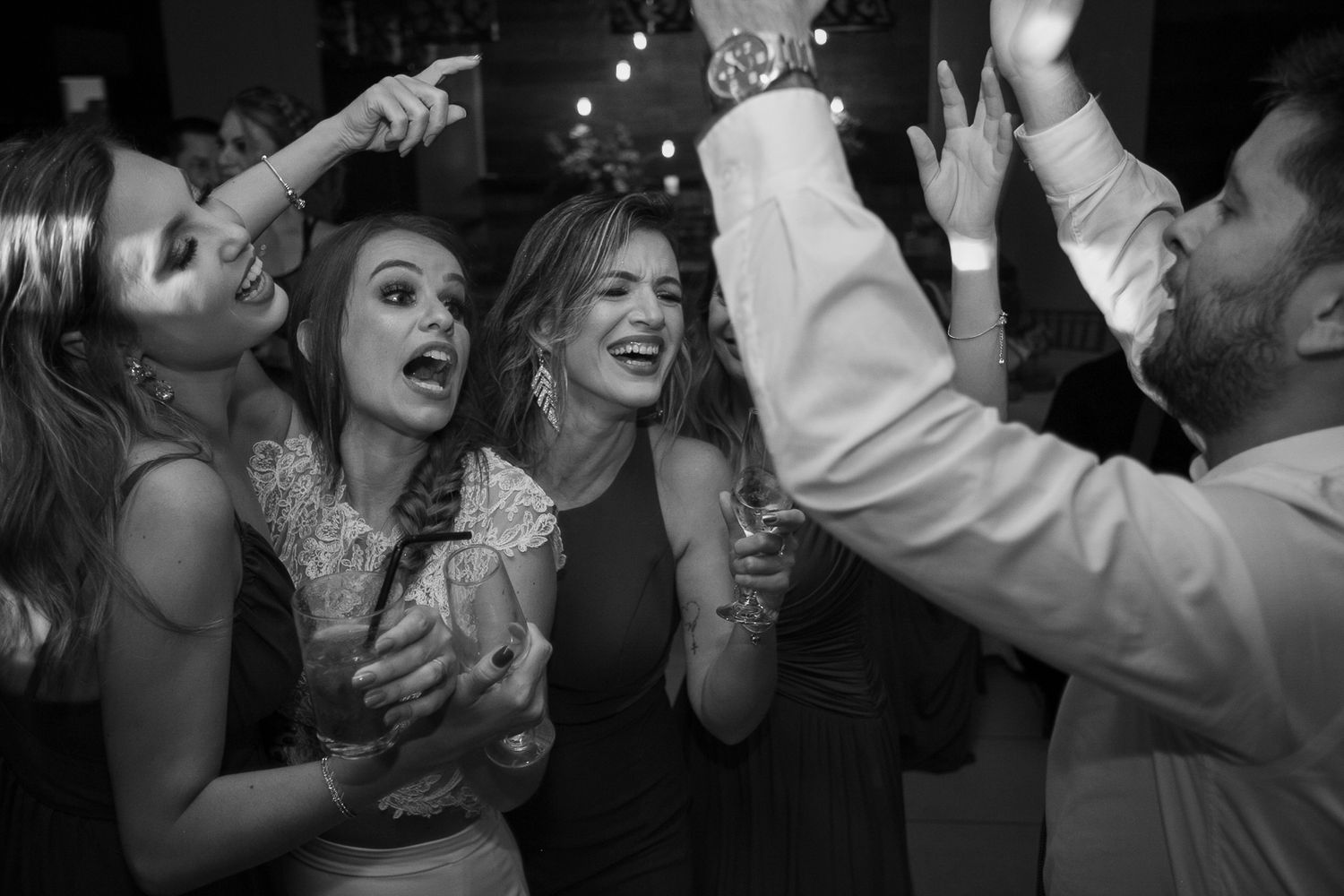 Candid black and white photo of joyful dancing at wedding reception.