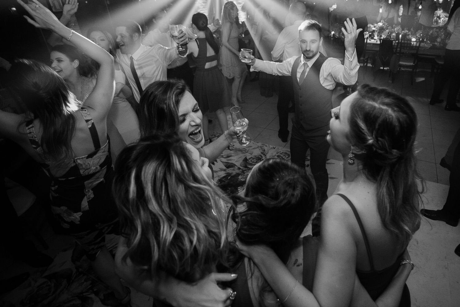 Black and white photo of energetic dance floor celebration at wedding reception.