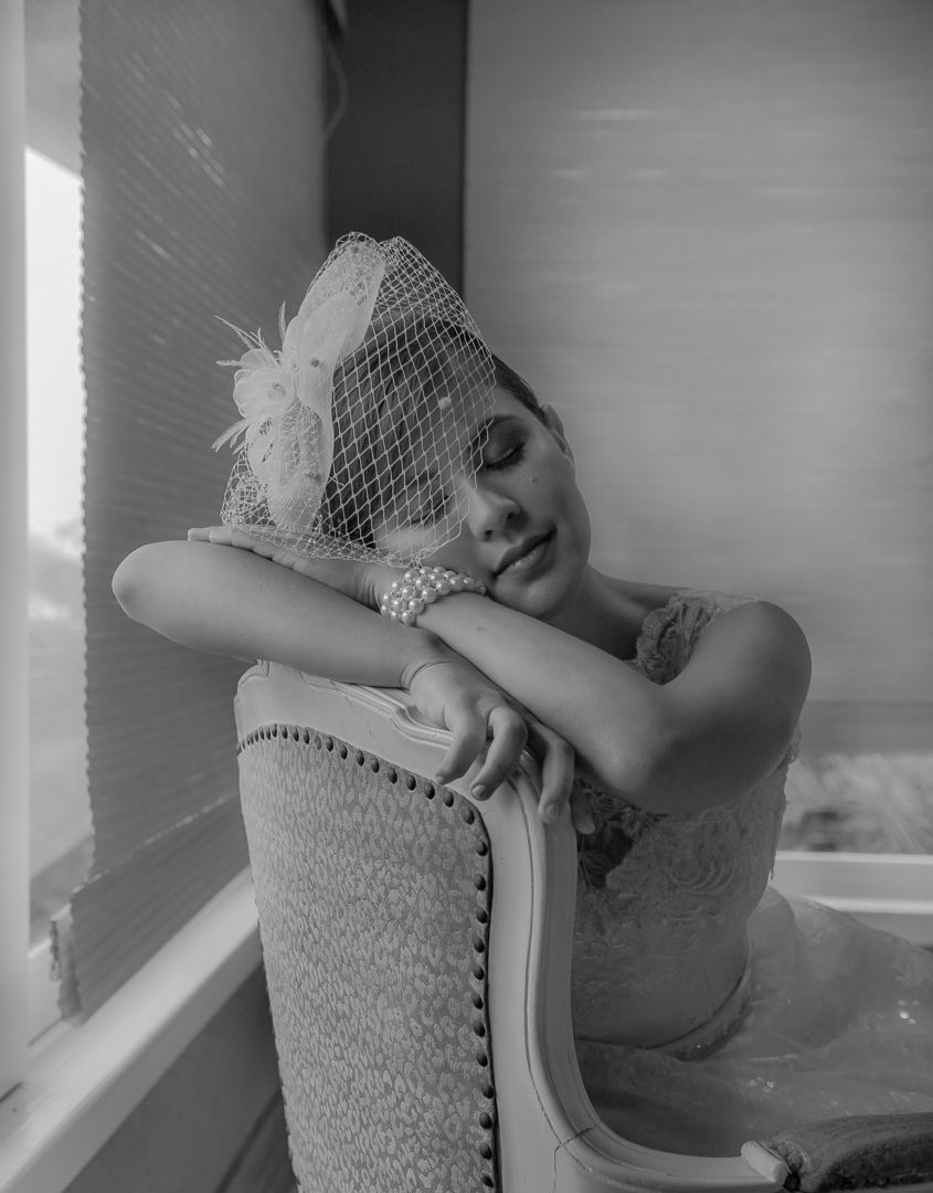 An elegant bridal portrait with vintage-style birdcage veil in classic black and white.