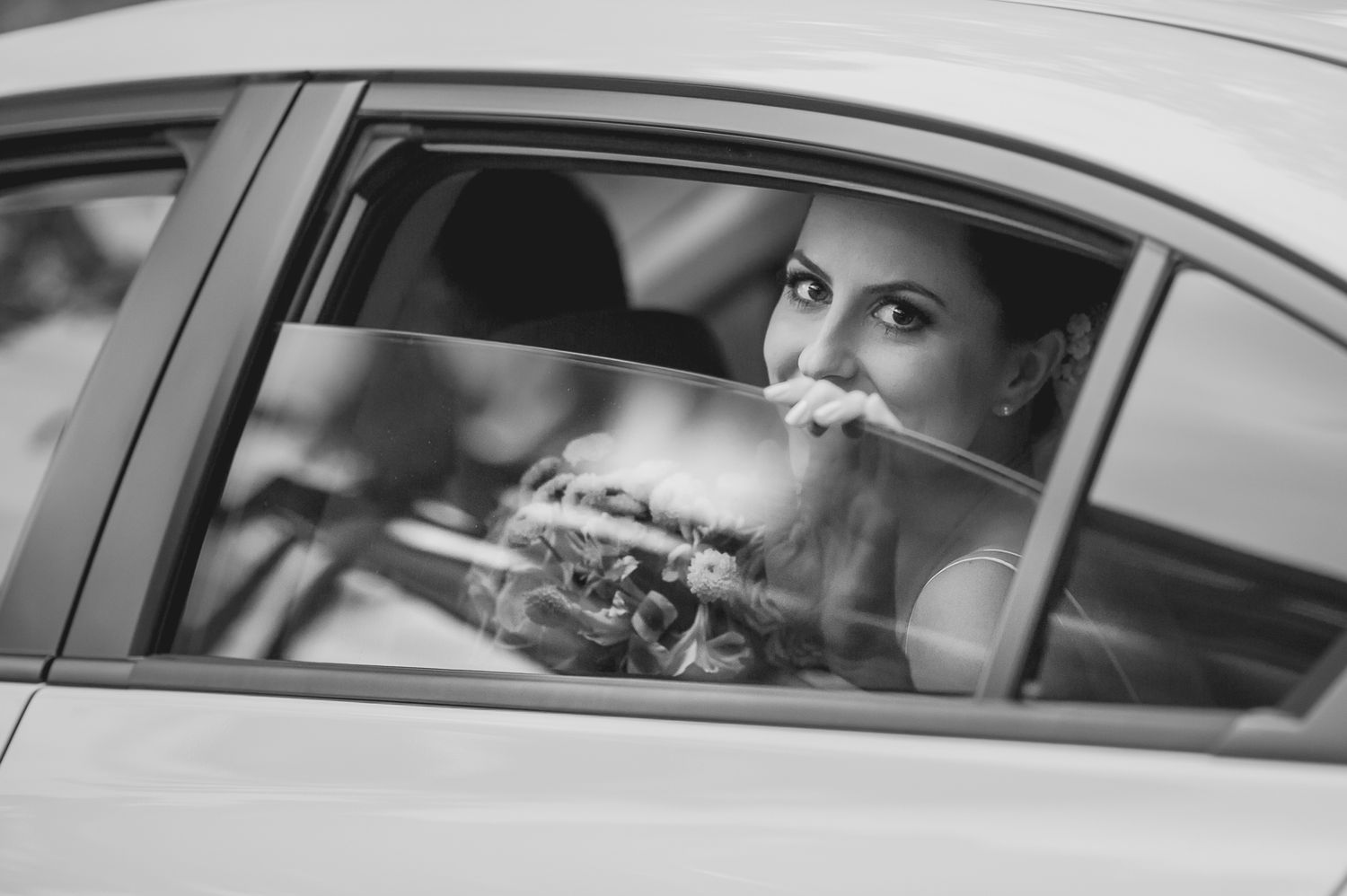 Black and white portrait through a car window showing an elegant moment.