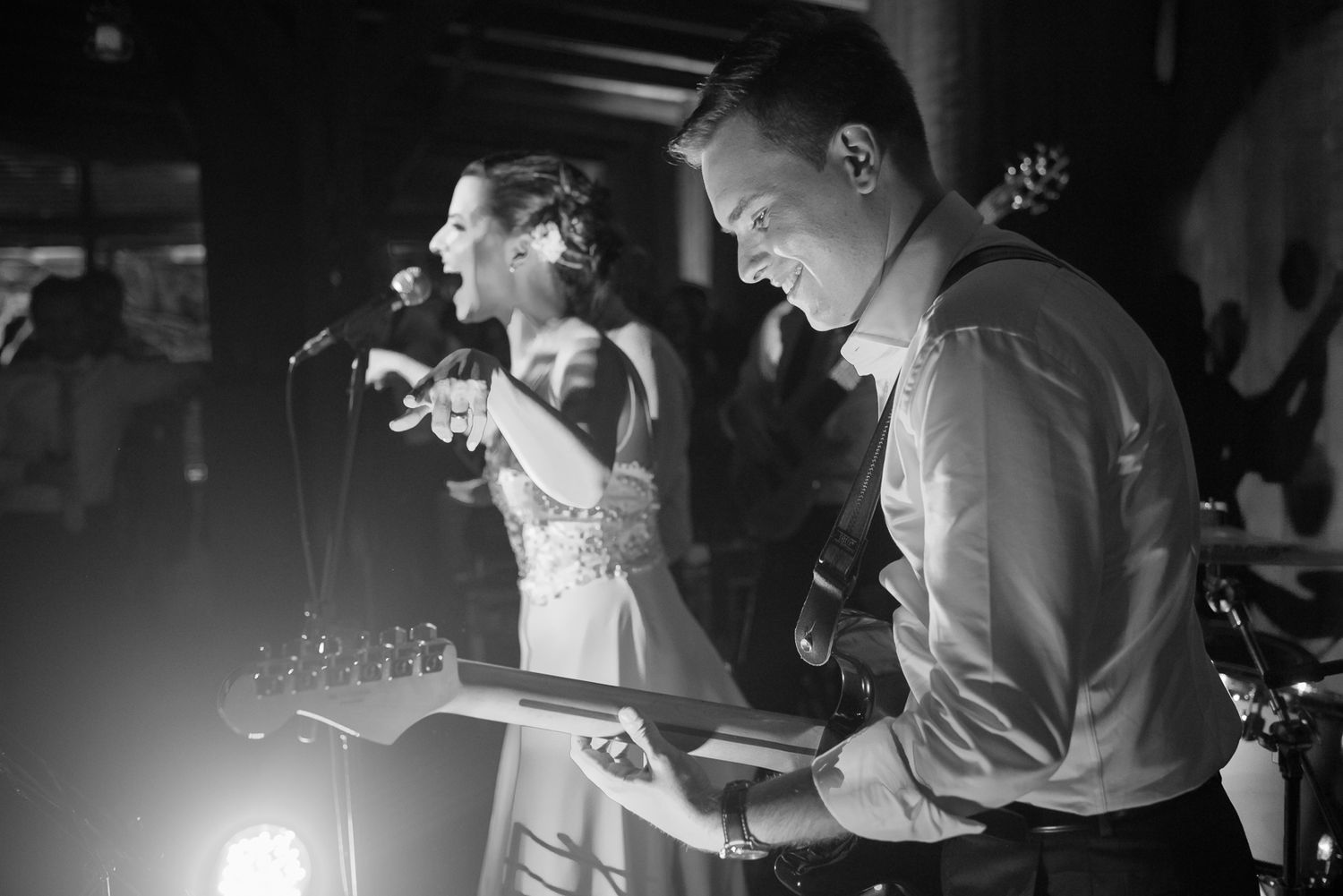 Wedding band performs at reception with musical instruments in black and white.