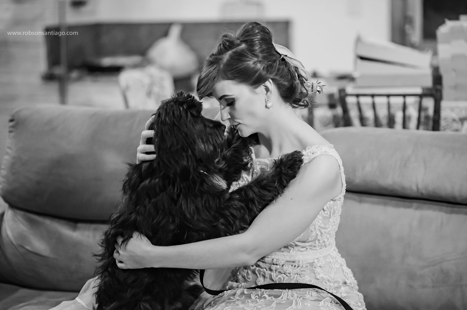 A tender moment between a bride in a white dress and her black dog.
