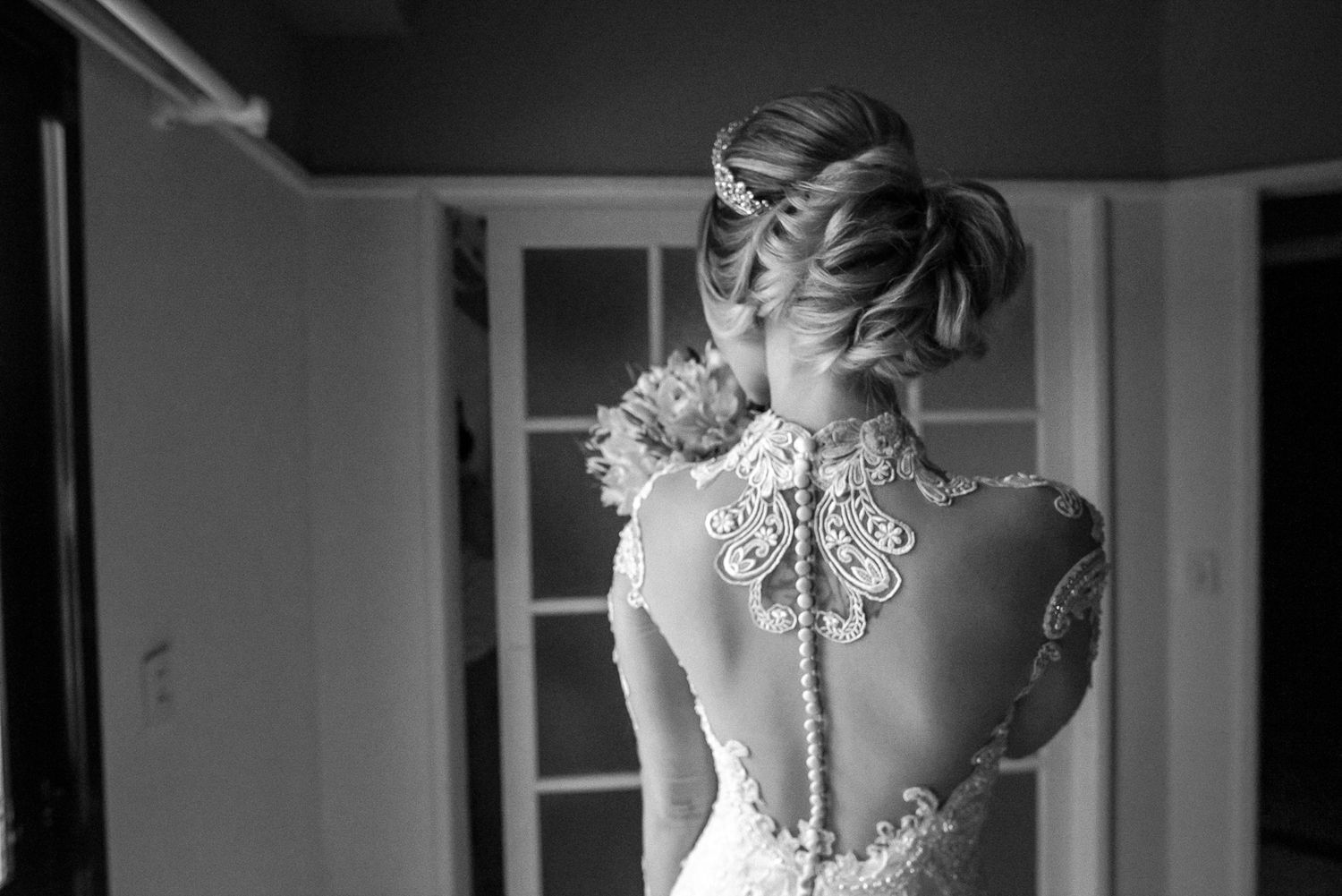 An elegant lace wedding dress with intricate back detail photographed in black and white.