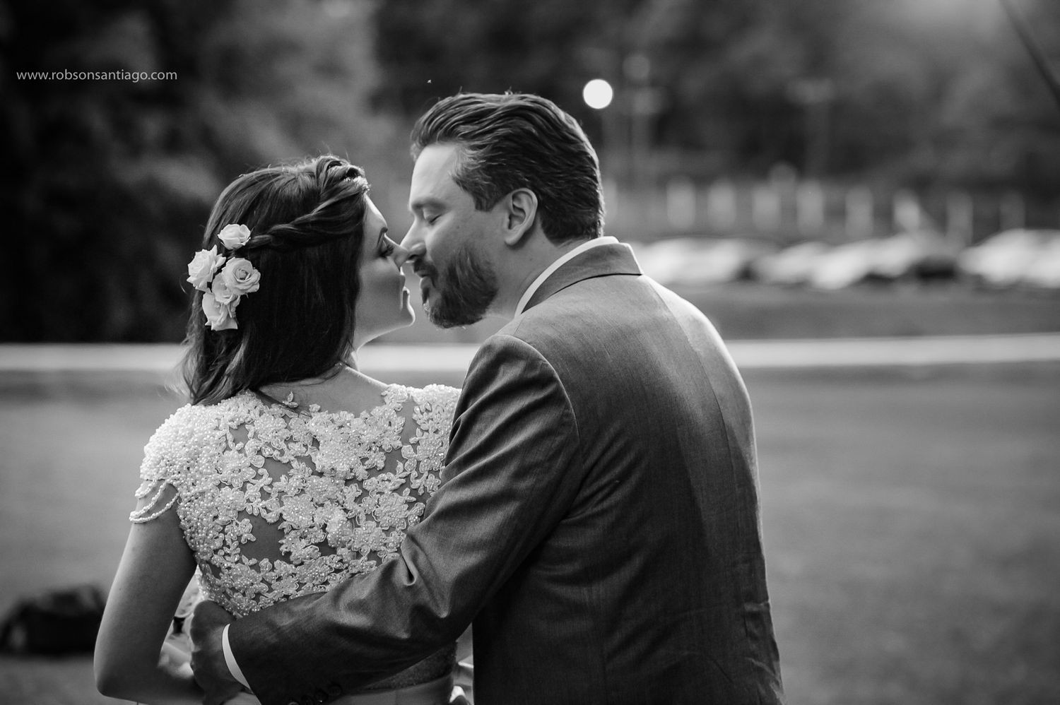 An intimate black and white portrait of newlyweds sharing a tender moment outdoors.