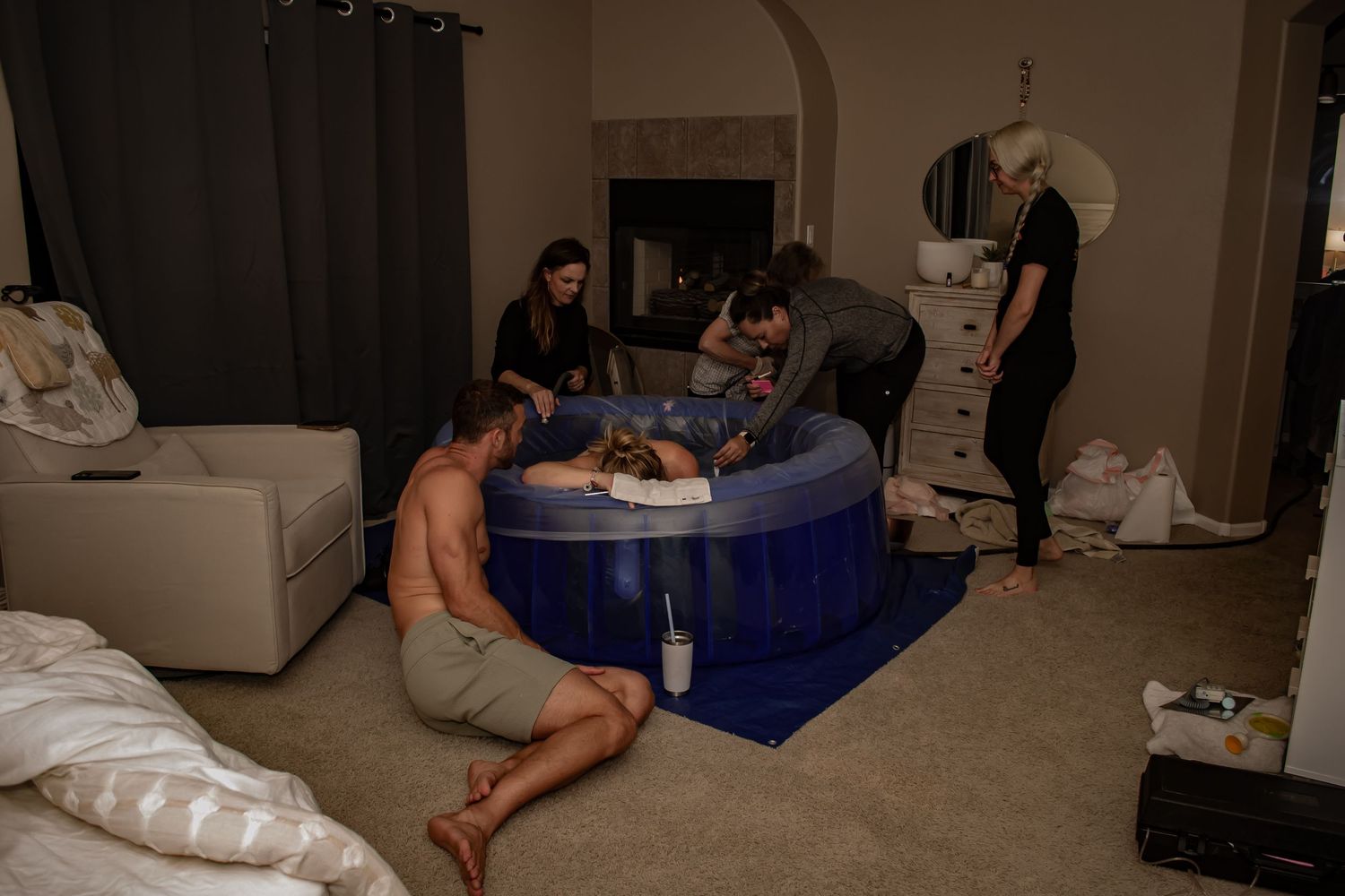 Image of a birthing team surrounding a pregnant woman who is laboring in a birthing tub in her home