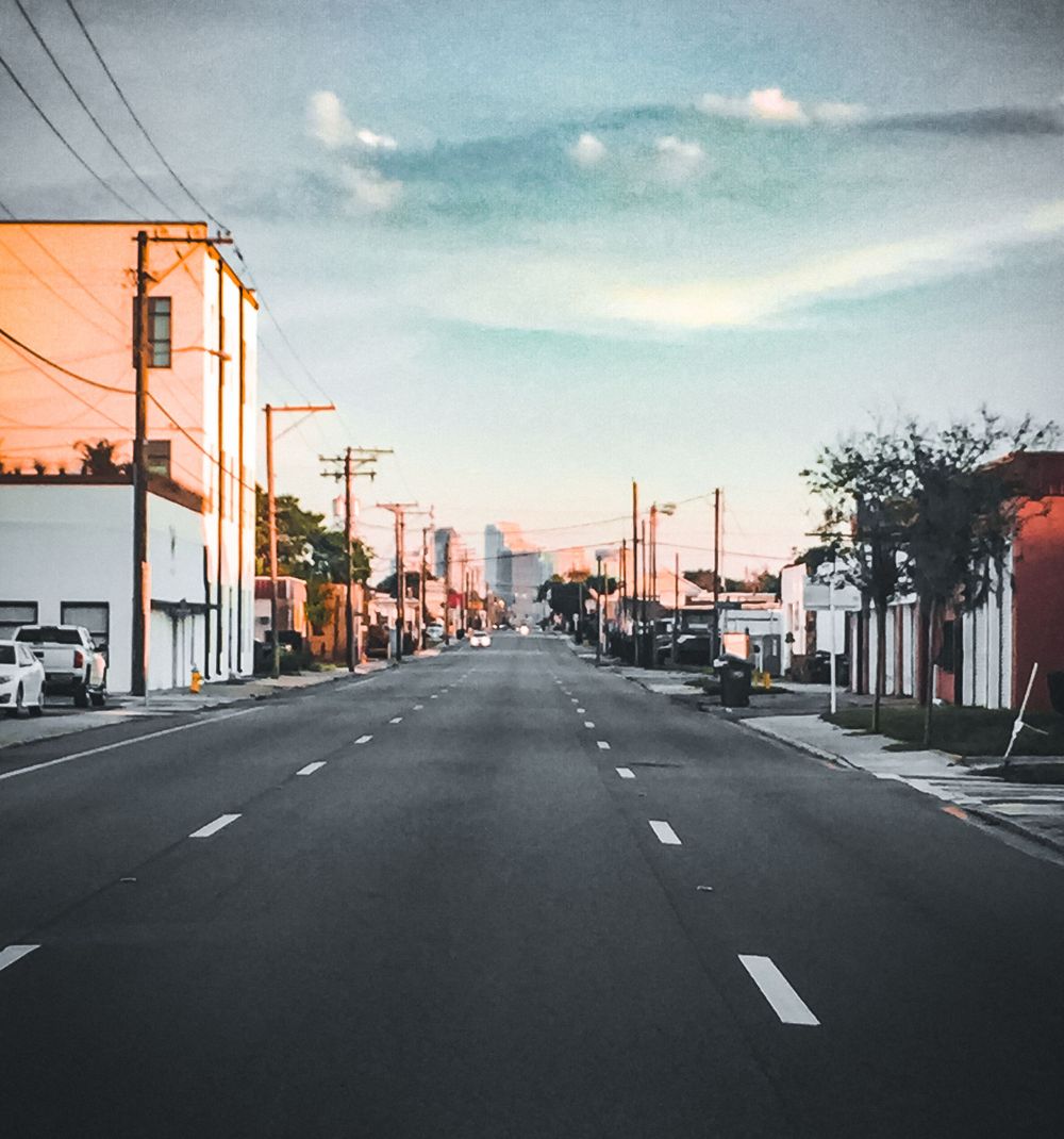Empty urban street with white lane markings stretching into the distance at sunset.