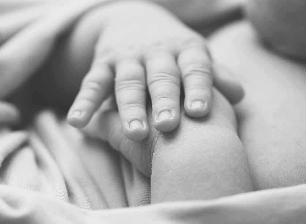 Close-up black and white photo of tiny newborn baby hand.