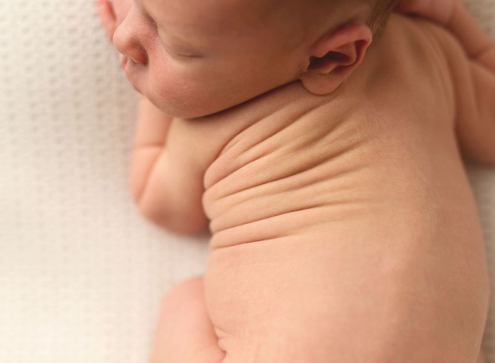 Close-up side view of sleeping baby swaddled in peach fabric.