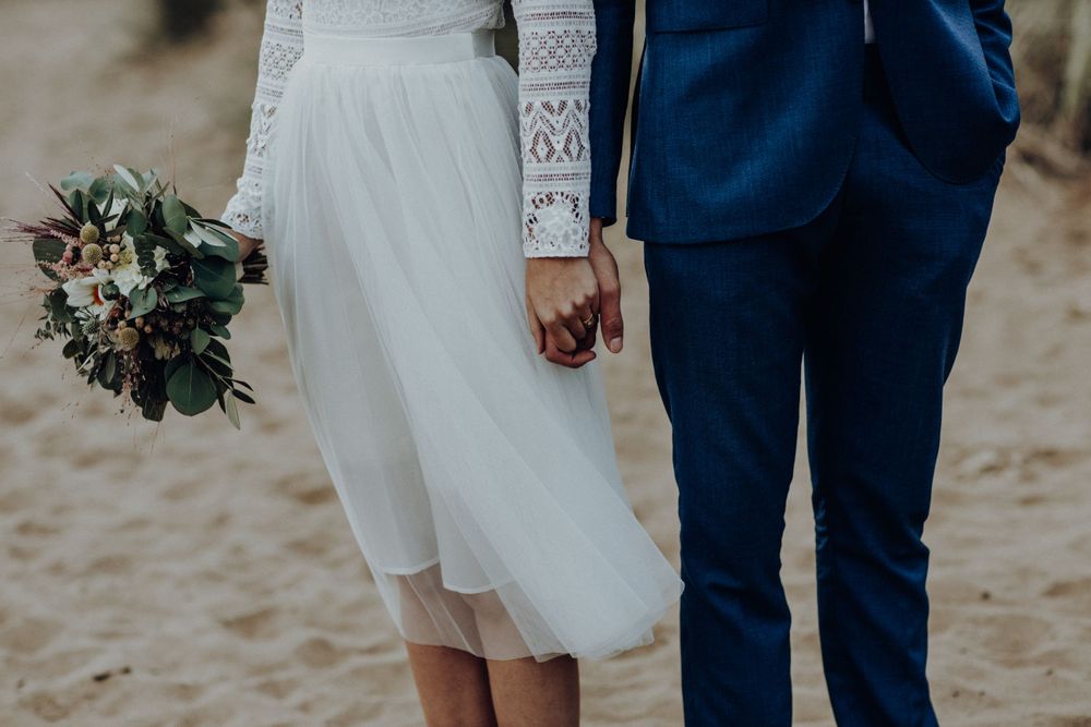 Hochzeitspaar Hand in Hand am Strand