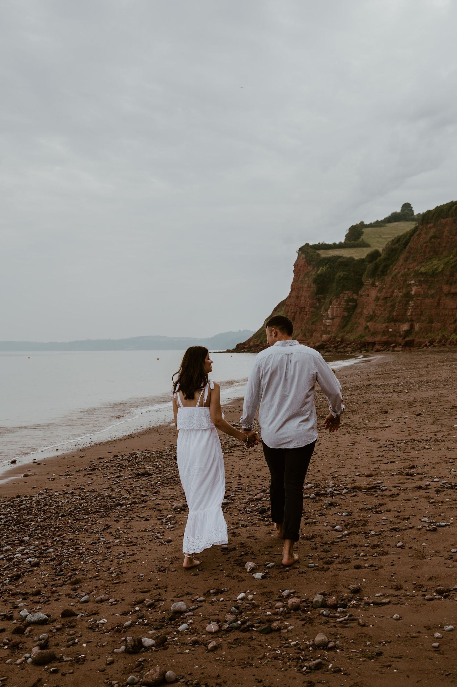 Couple walking on the sand at a beach in Teignmouth.