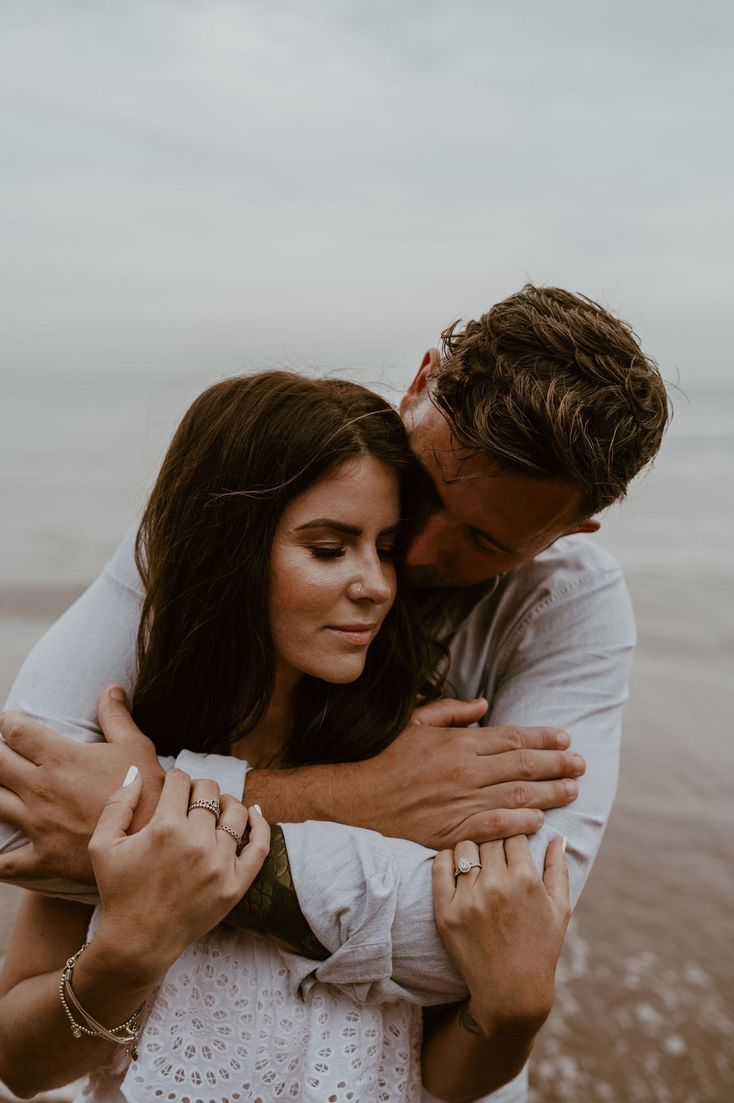 Couple embracing together in a cuddle with the sea in the background.