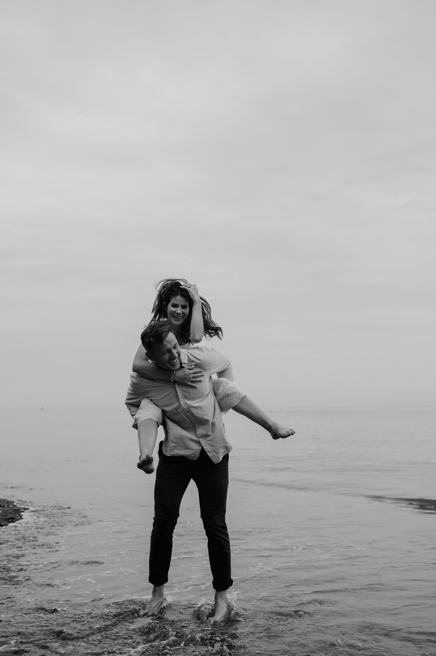 Couple piggybacking on the beach for their couples photoshoot at Teignmouth.
