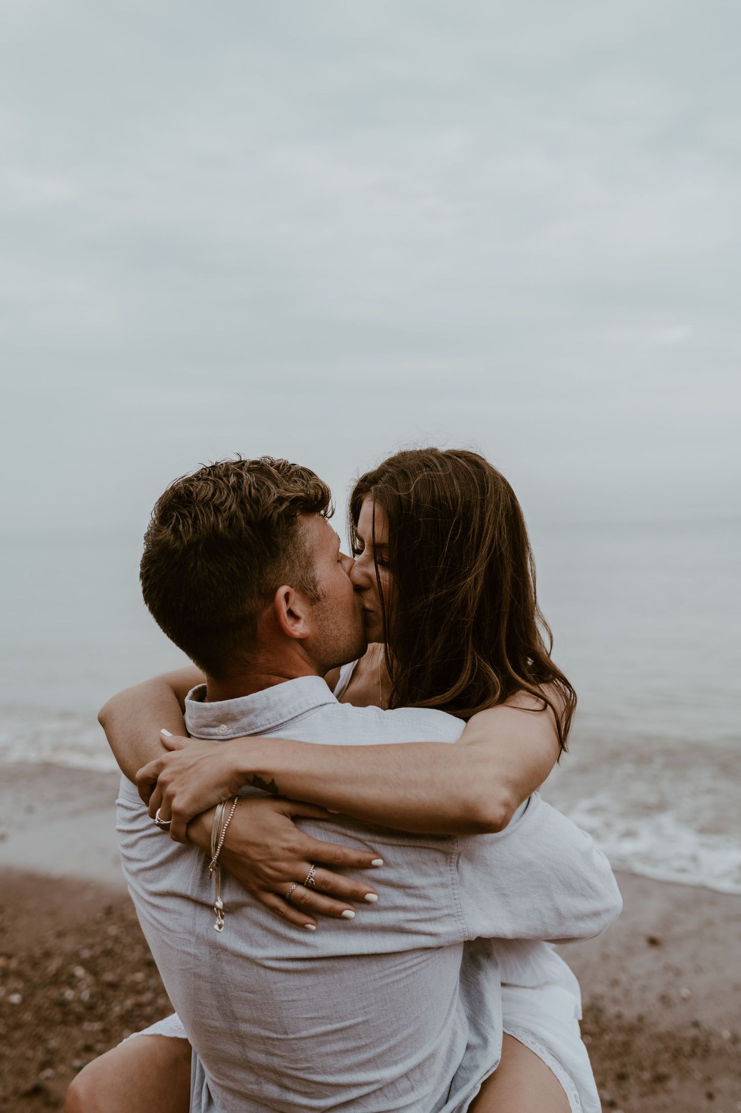 A beach engagement shoot with a couple kissing in the sand.