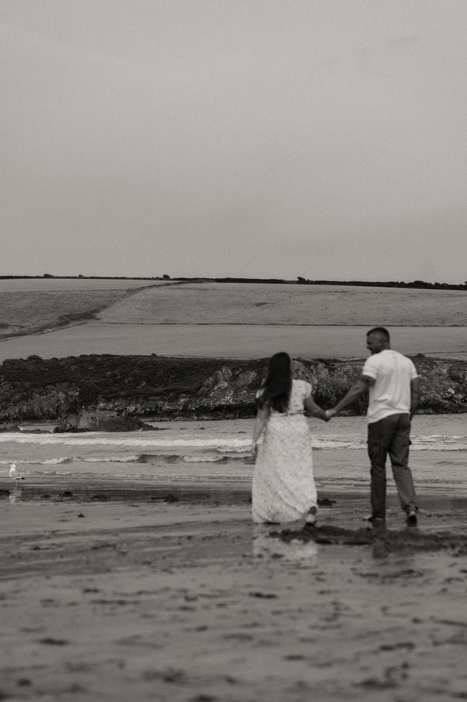 Black and white image of a couple walking on Mothecombe Beach
