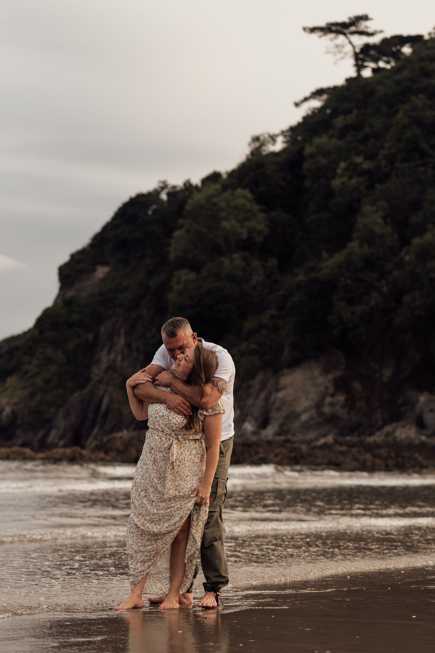 Happy couple playing on the beach for their engagement shoot at Mothecombe Beach