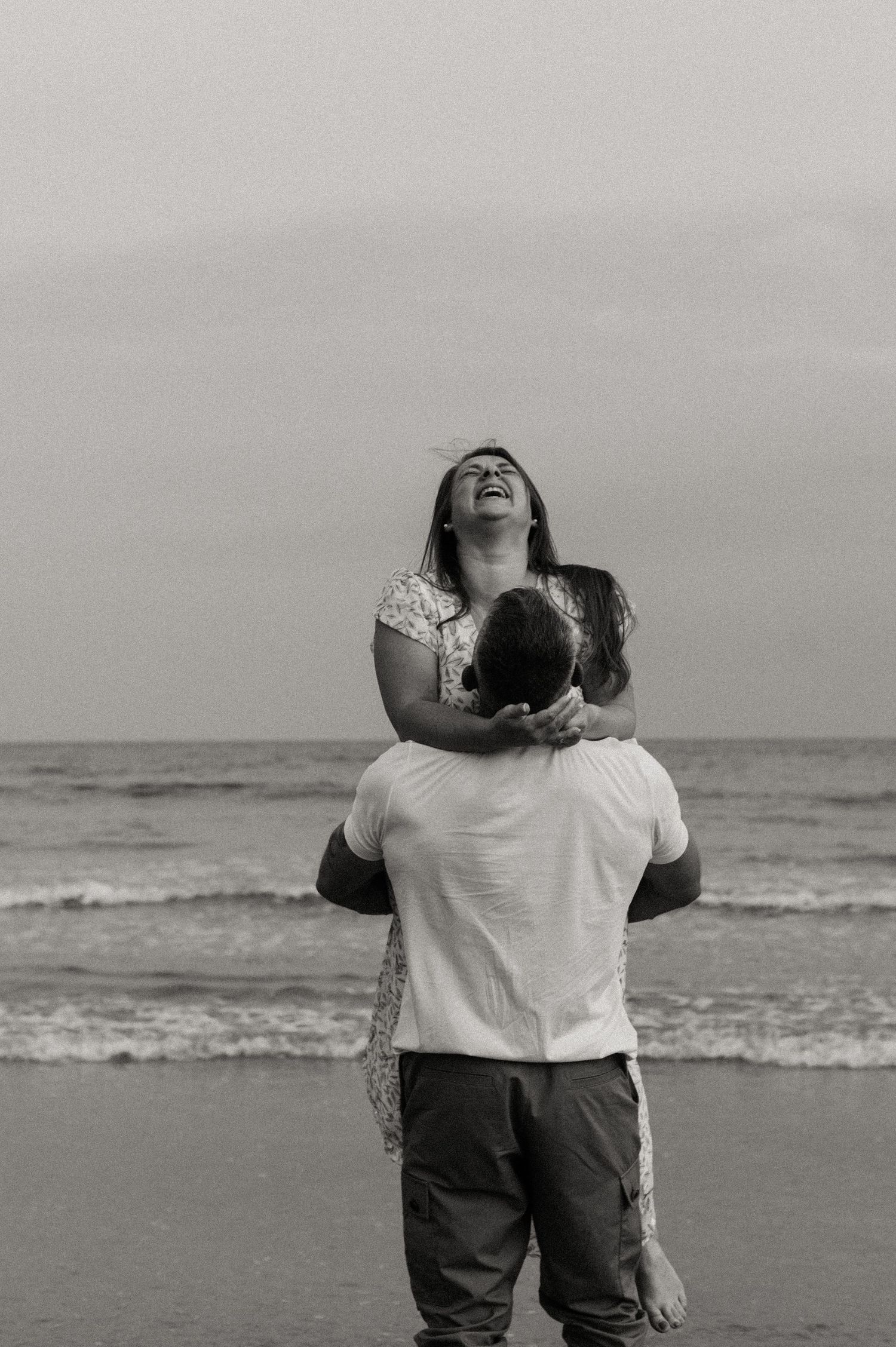 man picking up his fiance and shes laughing on their couples photoshoot
