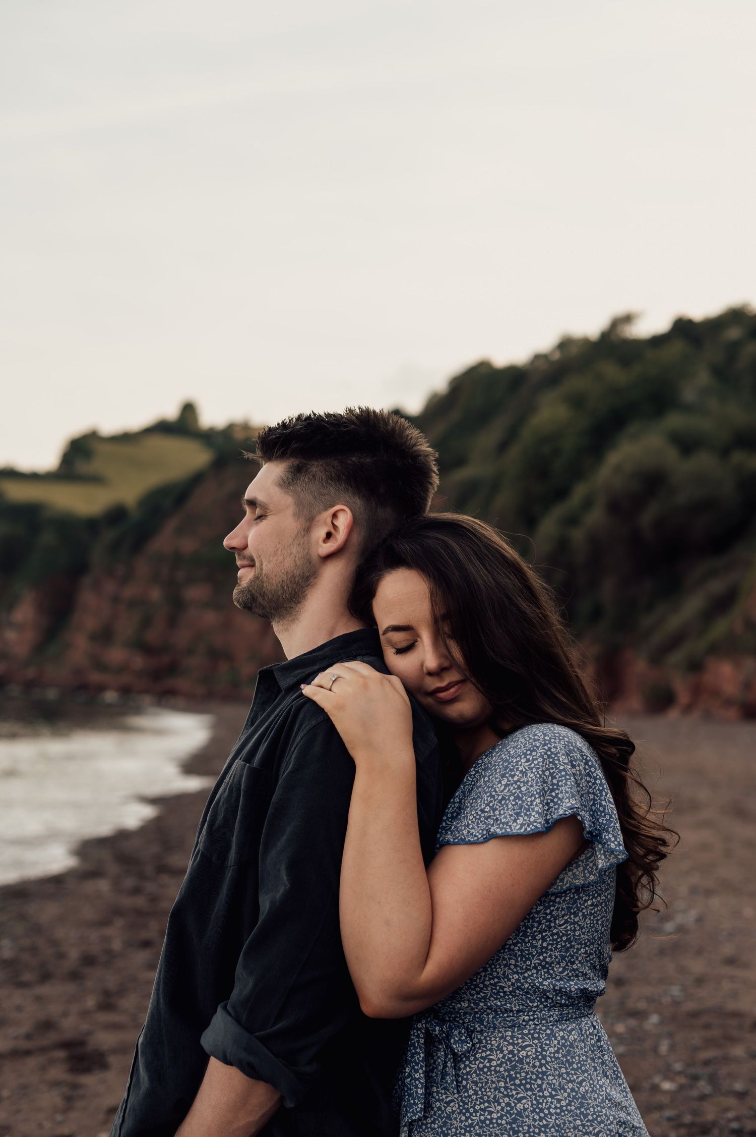 Woman hugging her fiances back on the beach at their Engagement shoot at Teignmouth Beach