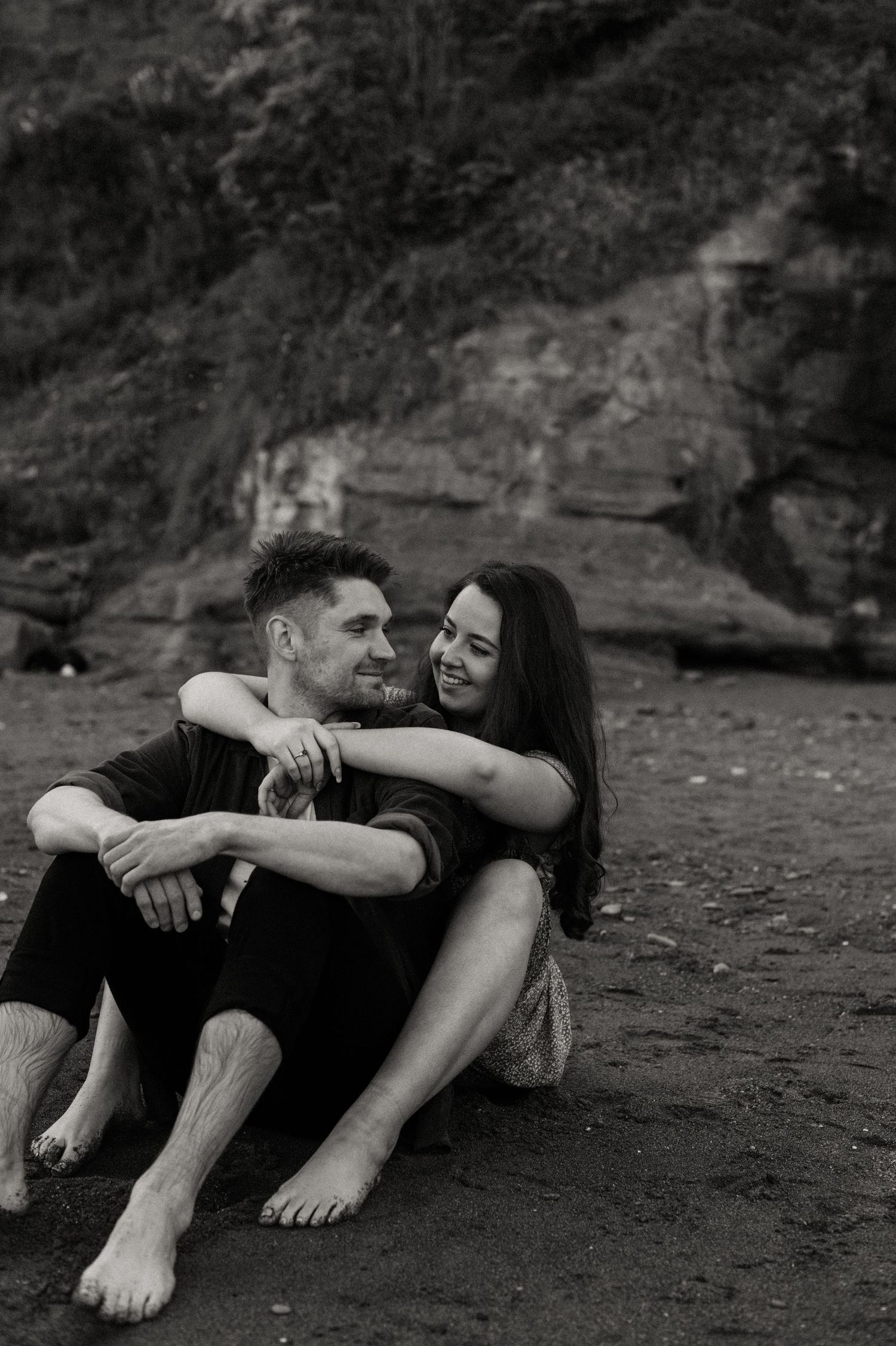 Happy couple sat on the beach with their feet in the sand at Shaldon Beach