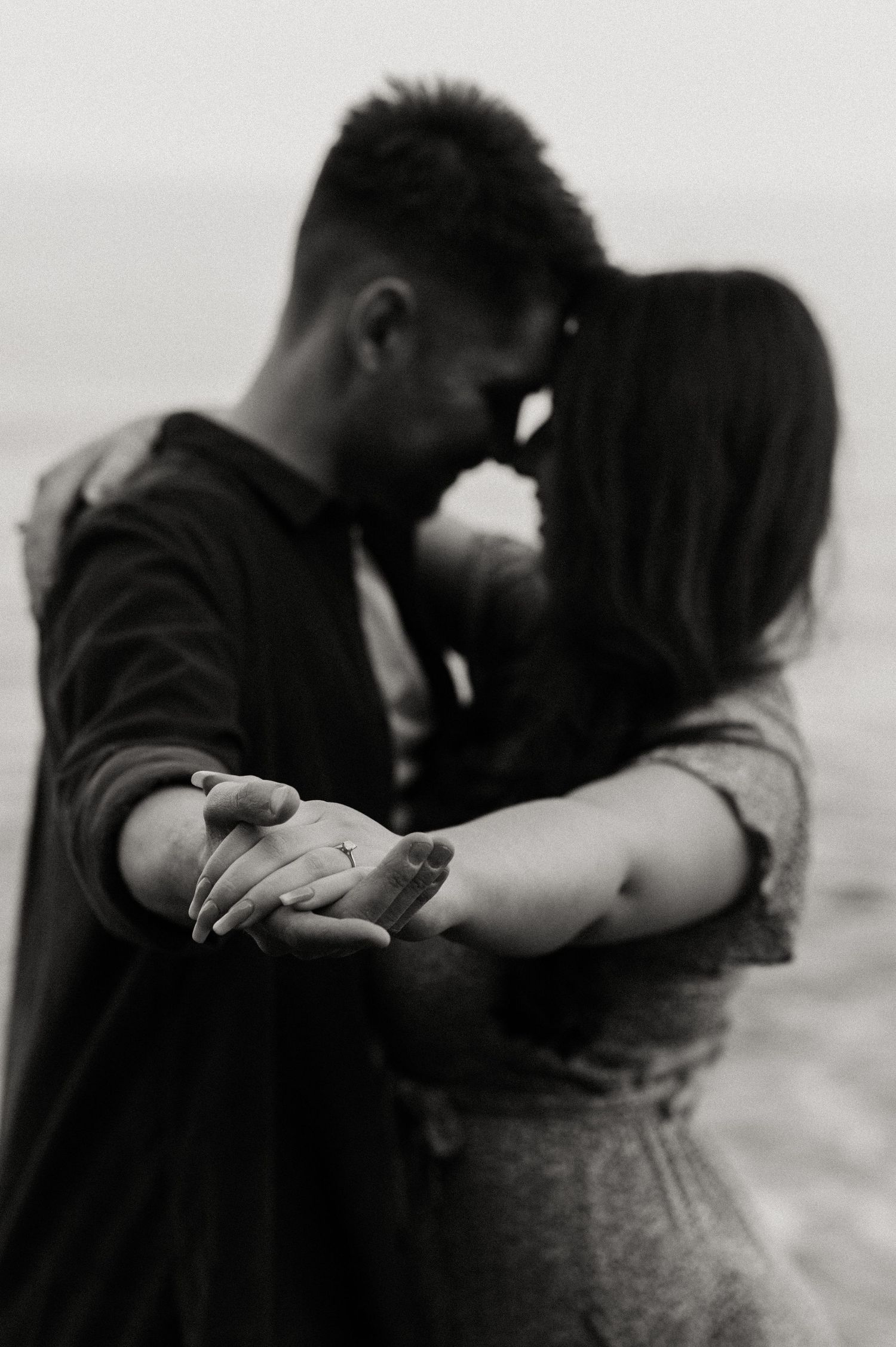 A couple embracing each other whilst showing the engagement ring