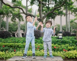 Playful family moment in a lush garden setting with blooming flowers.