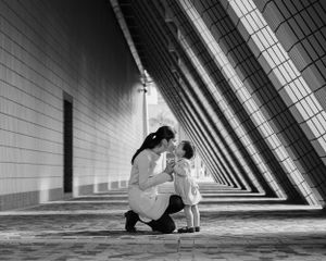 Black and white photo of people in geometric tunnel with dramatic shadows and lines.