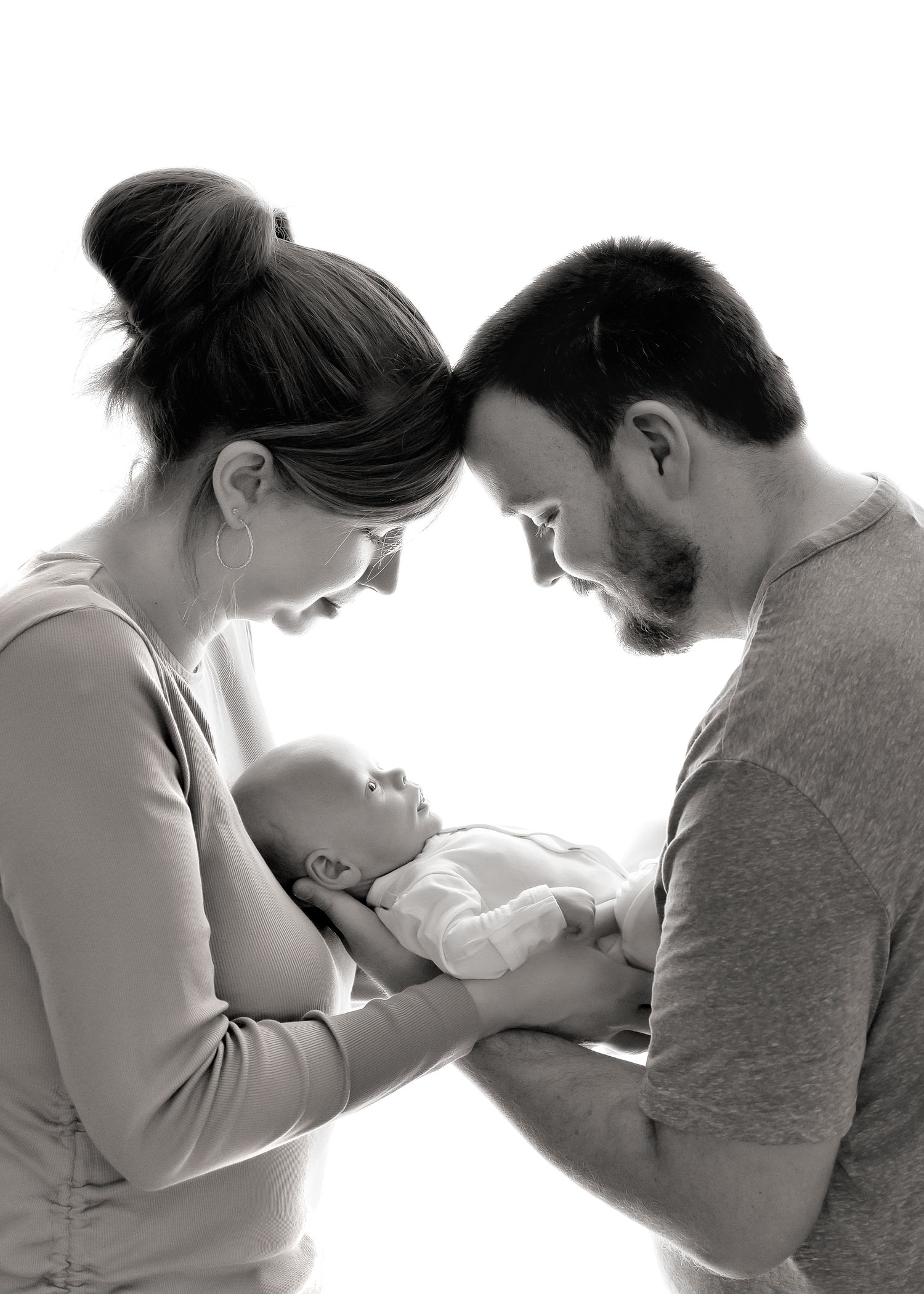 Newborn photography photoshoot with mom and dad looking at baby