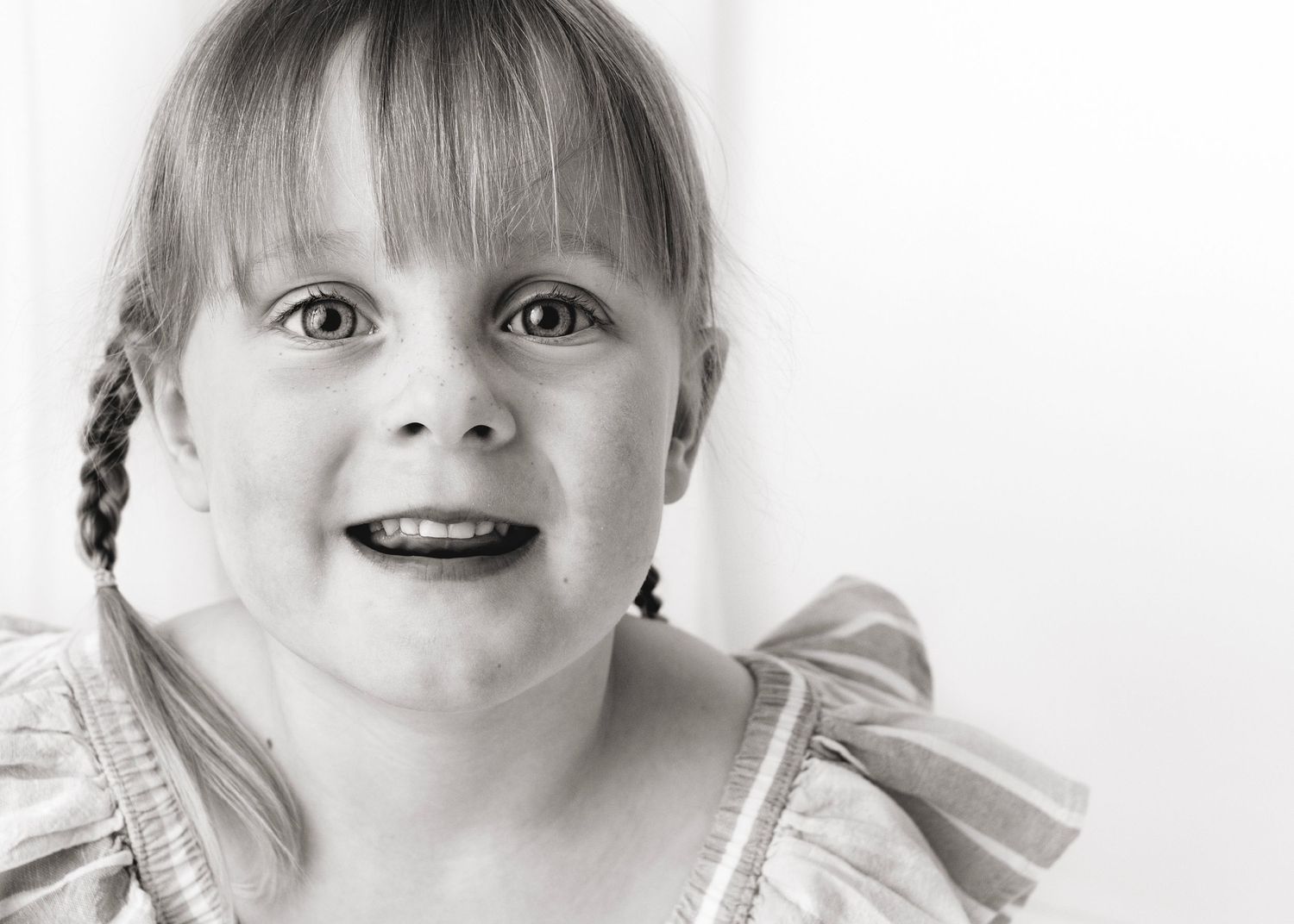 Young girl smiling for camera in black and white - photography by Tracy McEwan