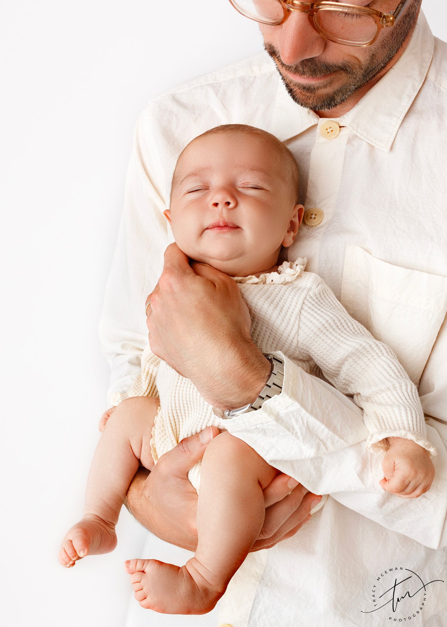 Dad holding new baby girl as she sleeps with a smile