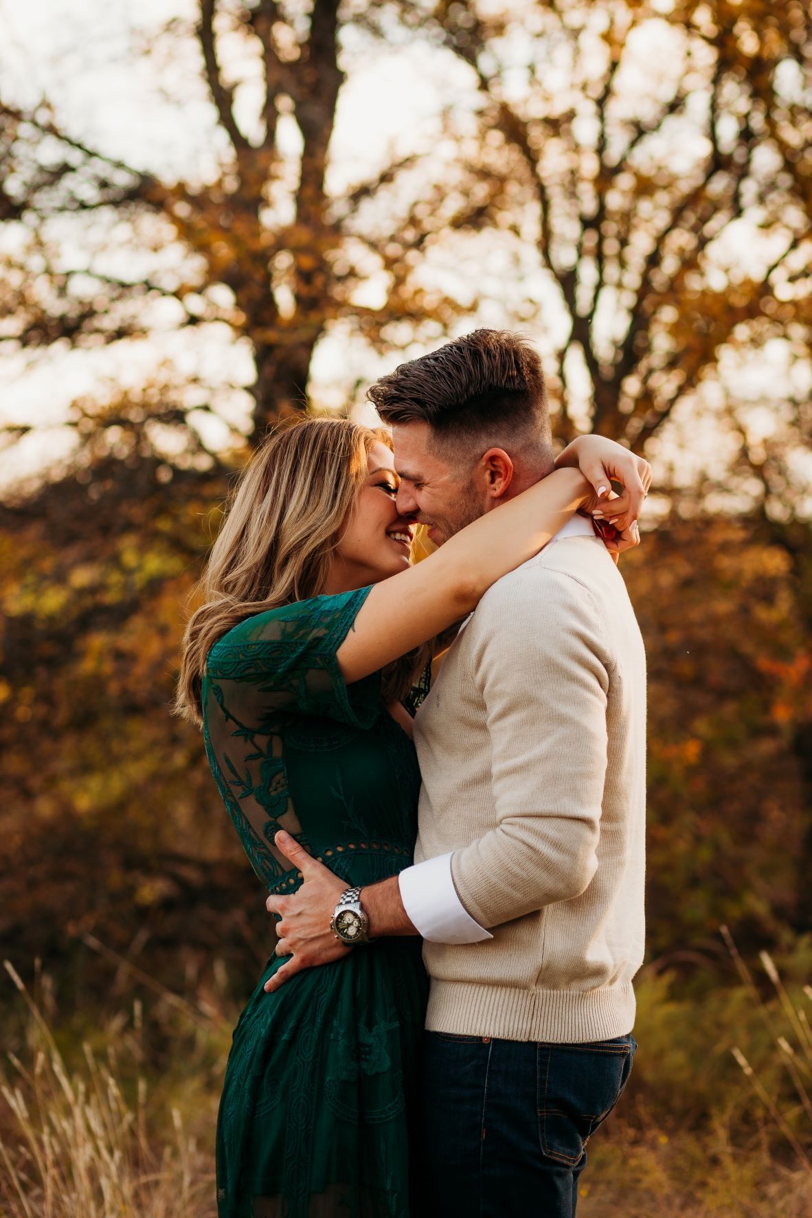 Newly engaged couple embracing and almost kissing outdoors at golden hour