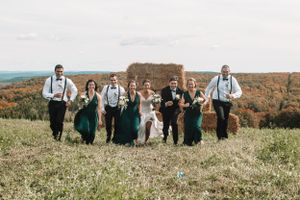 Wedding party walking through autumn field with mountain landscape in the background.