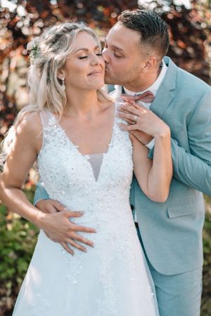 Intimate wedding portrait featuring a mint suit and lace wedding gown in natural lighting.