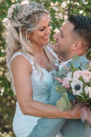 Joyful wedding couple sharing a tender moment with soft bokeh and floral bouquet.