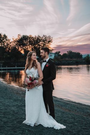 Sunset wedding portrait by a lake with dramatic sky.