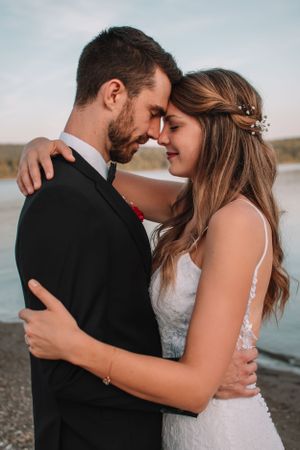 Wedding couple embracing by a lake during sunset.