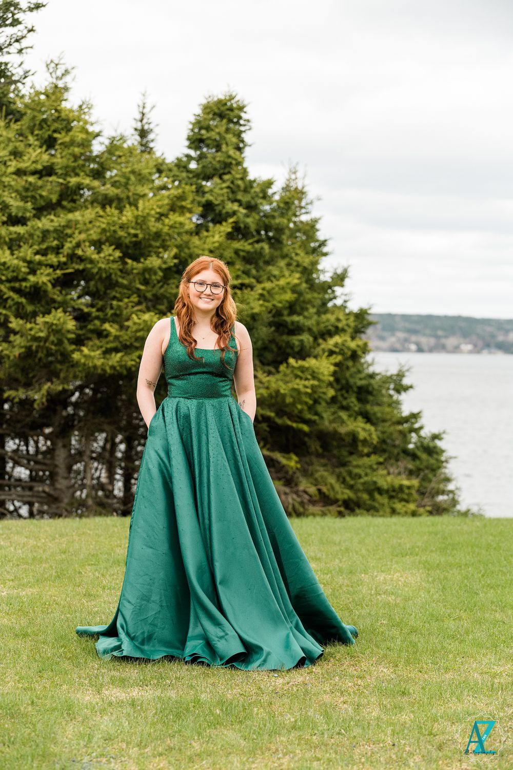 Full-length portrait of emerald ball gown against coastal landscape.