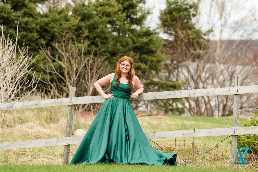 Flowing emerald dress captured in dramatic pose against coastal scenery.