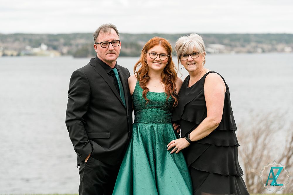 Family portrait by waterfront with emerald formal dress and dark attire.