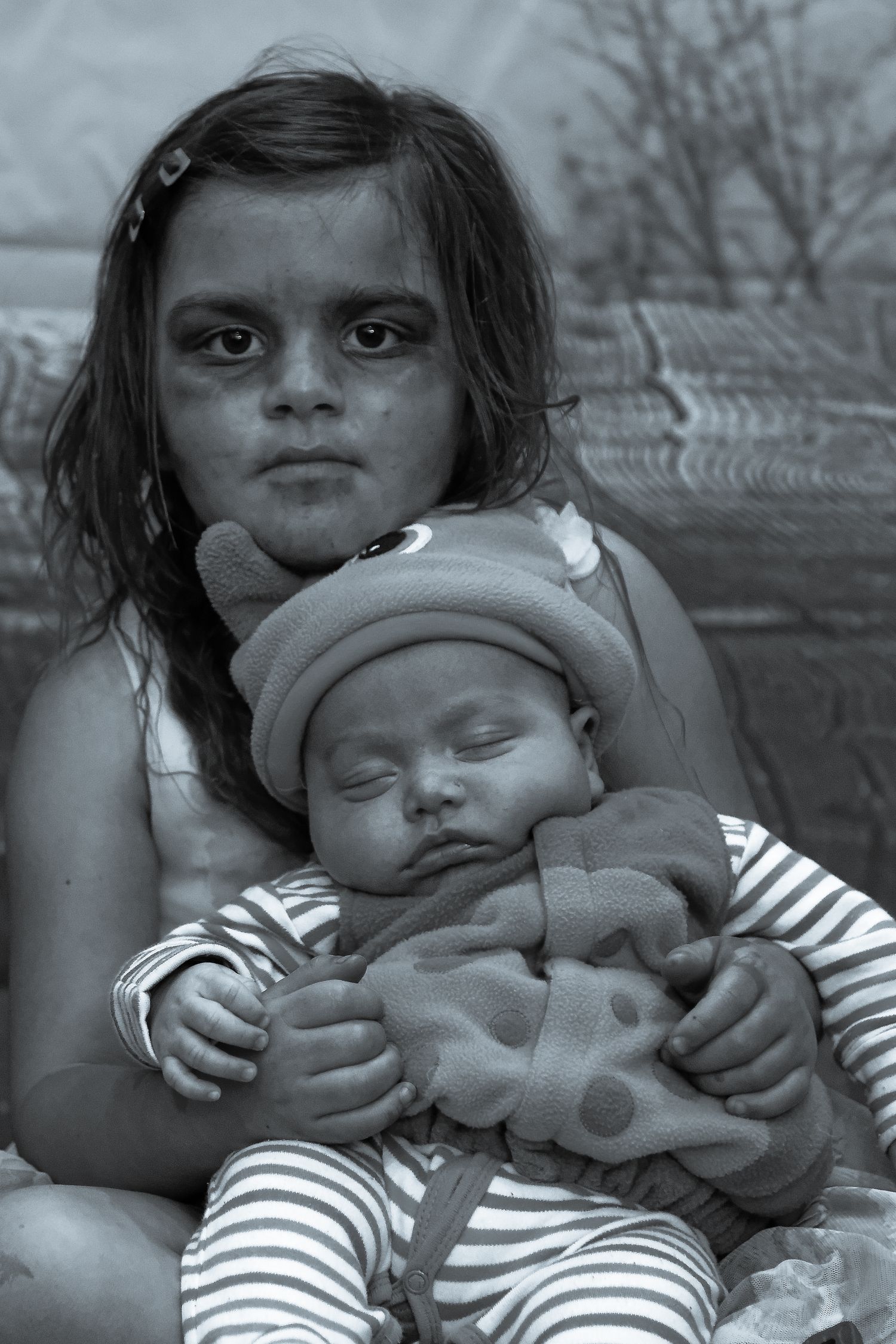Haunting black and white portrait showing children and baby with dramatic lighting.
