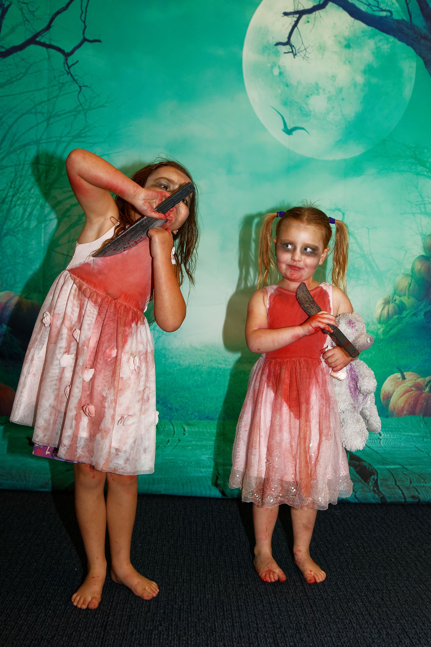 Two figures in pink dresses pose dramatically against a spooky green moonlit backdrop.