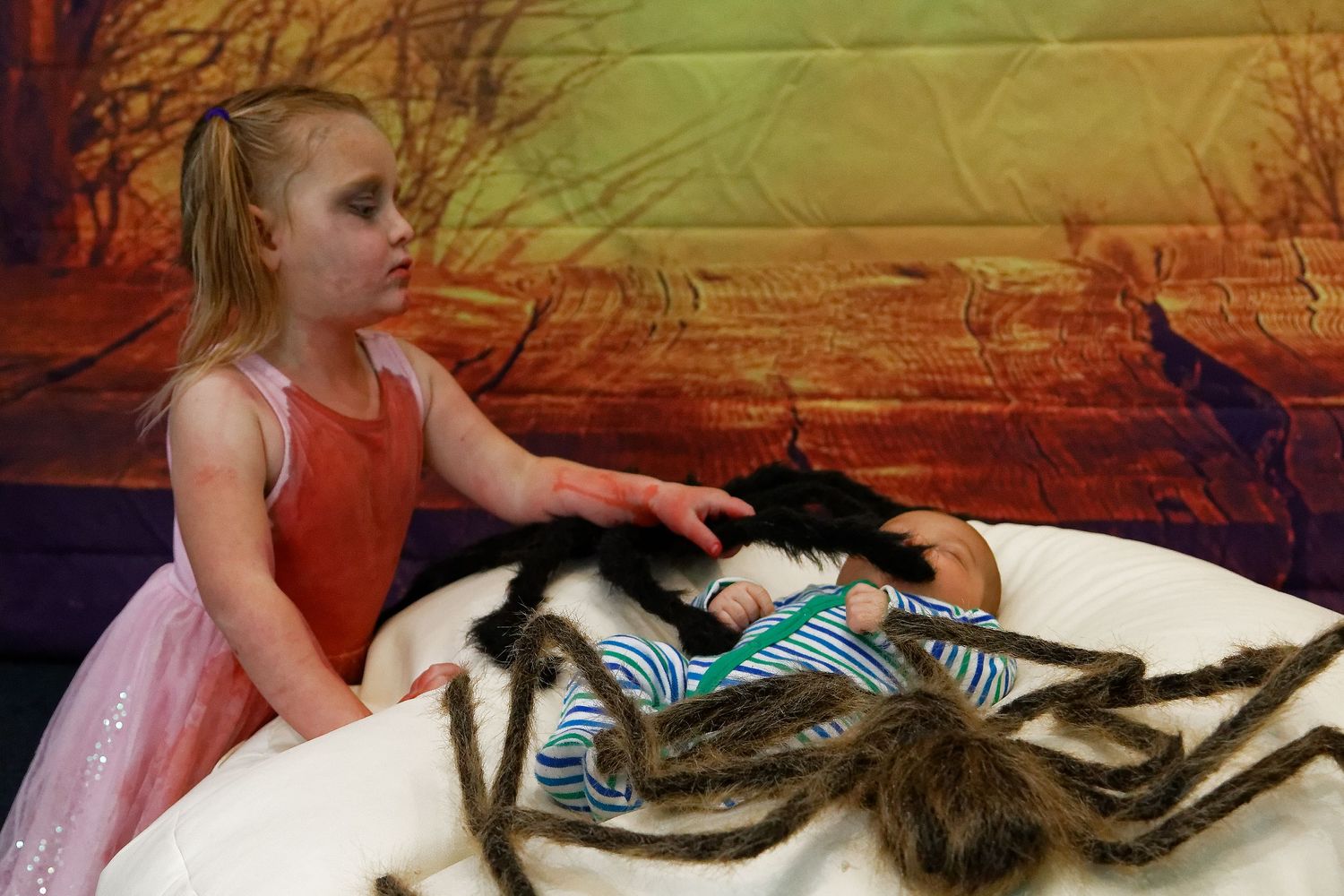 Child playing with striped puppets on white bean bag against orange backdrop.